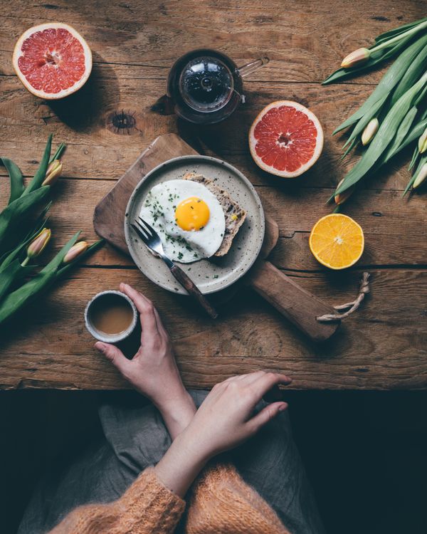Ein gedeckter Frühstückstisch mit Ei, Brot, Früchten und Kaffee. Foto von Daniela Constantini / Pexels.
